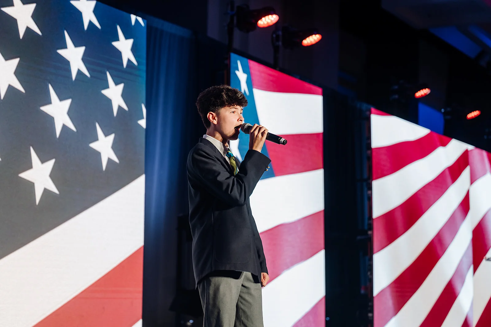 Young vocalist performing the national anthem on stage with American flag LED backdrop at USHCC National Conference in Atlanta
