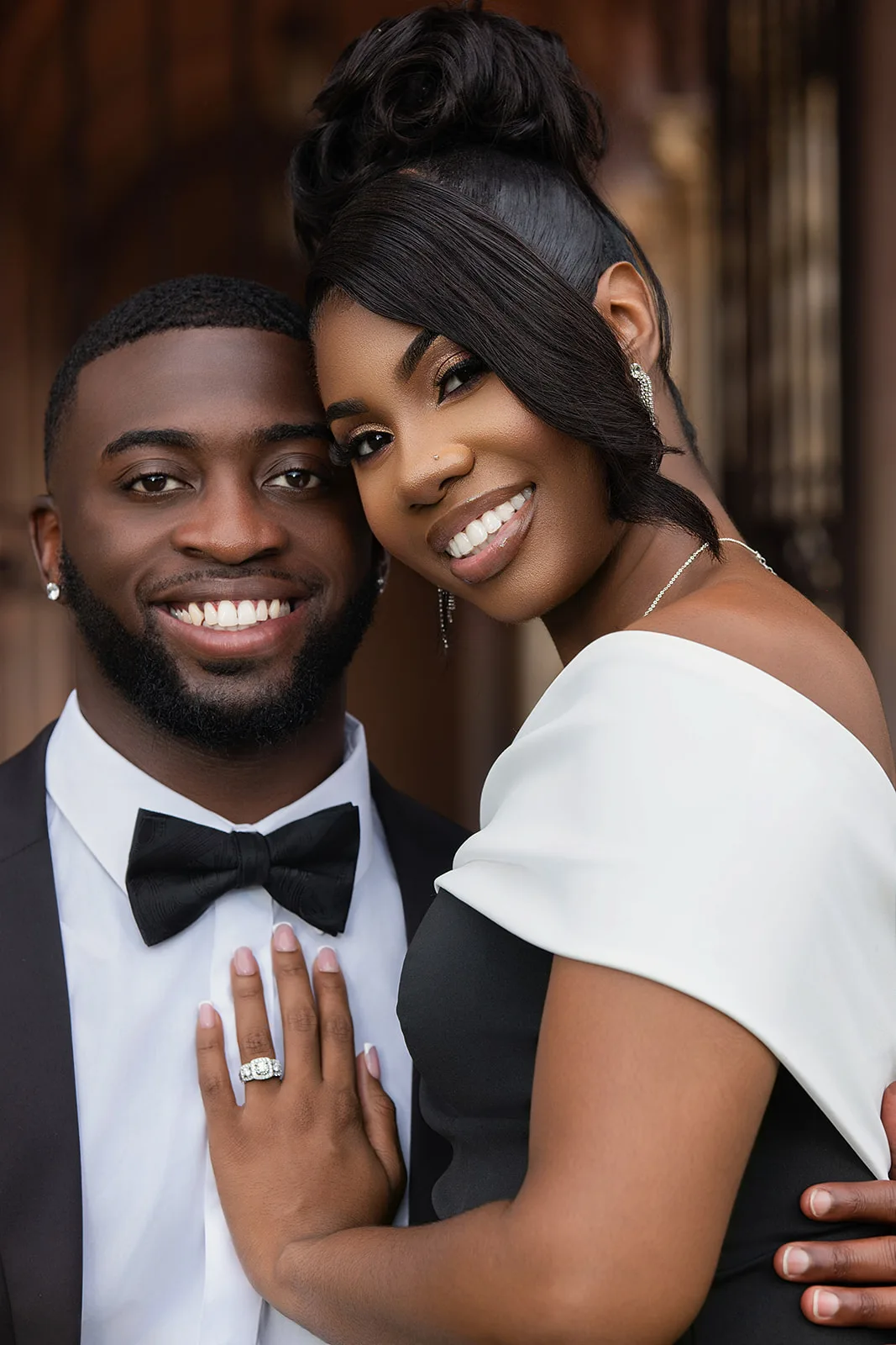 Close-up engagement portrait of smiling couple in black tie attire