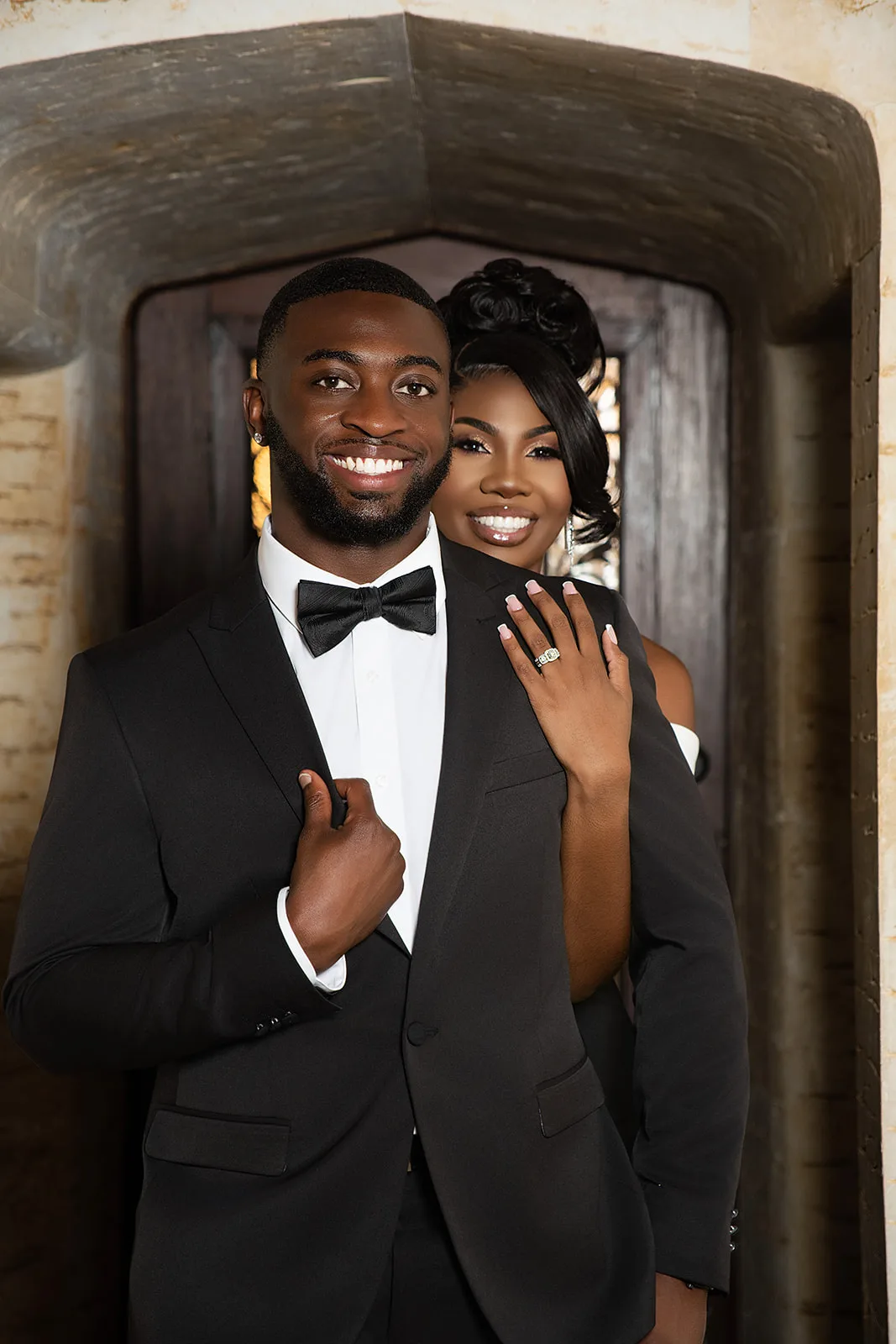 Elegant couple in tuxedos in stone archway