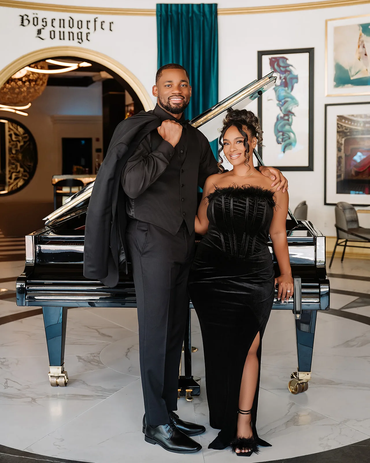 Black tie couple by grand piano in luxury lounge engagement session