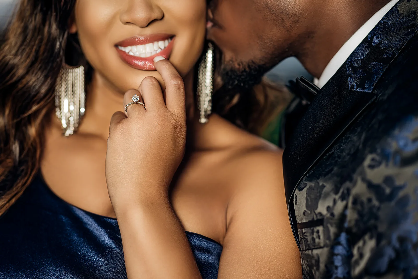 Detail shot of engagement ring with couple embracing