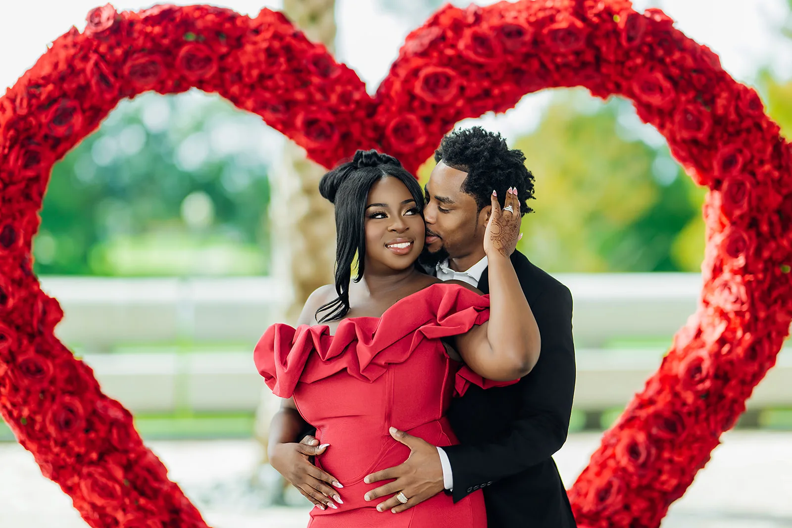 Couple in red rose heart arch engagement portrait