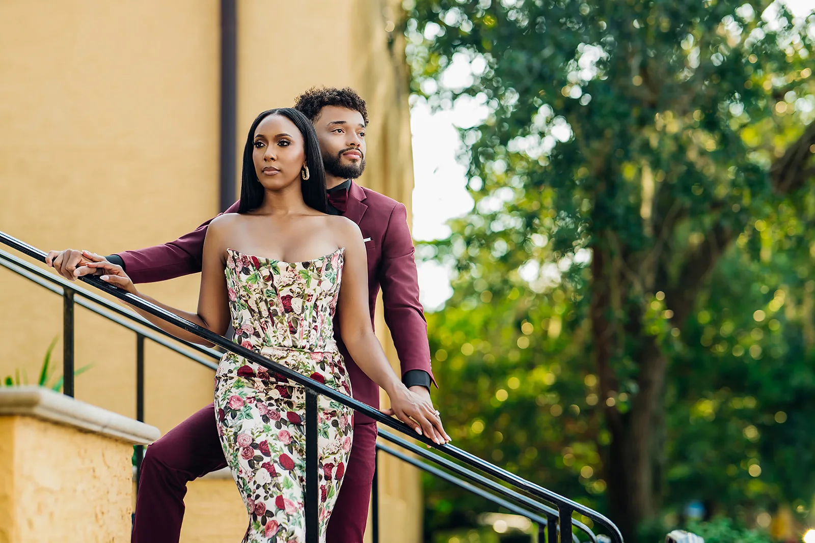 Elegant couple on staircase in burgundy suit and rose print dress
