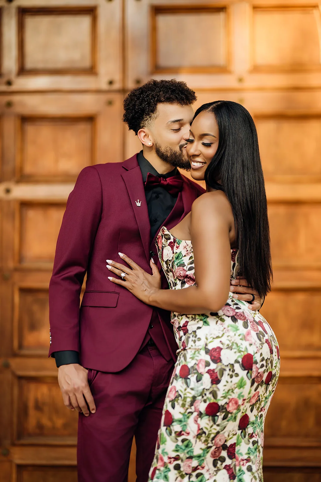 Intimate kiss between couple in floral gown and burgundy suit