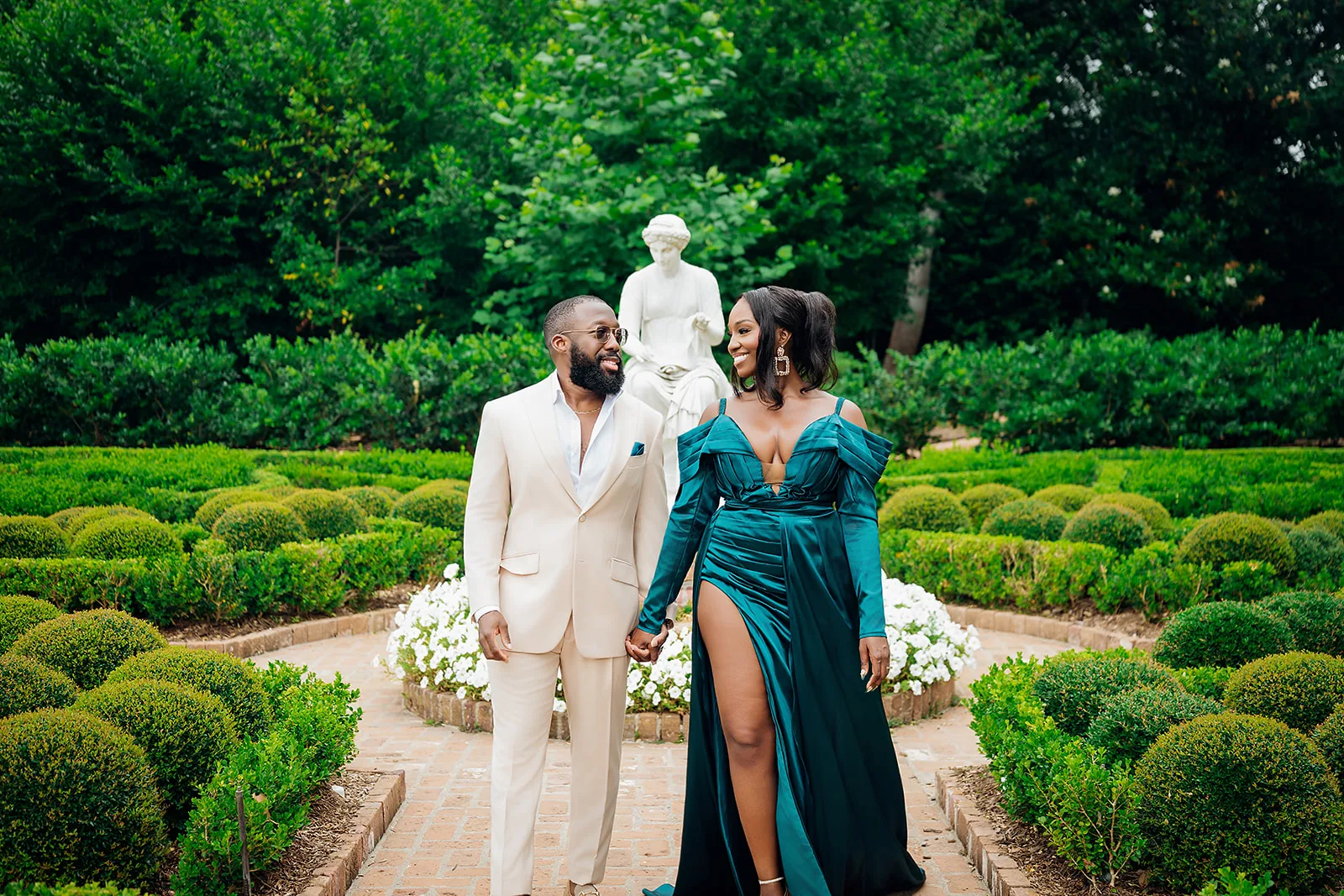 Couple in emerald gown and cream suit in formal garden
