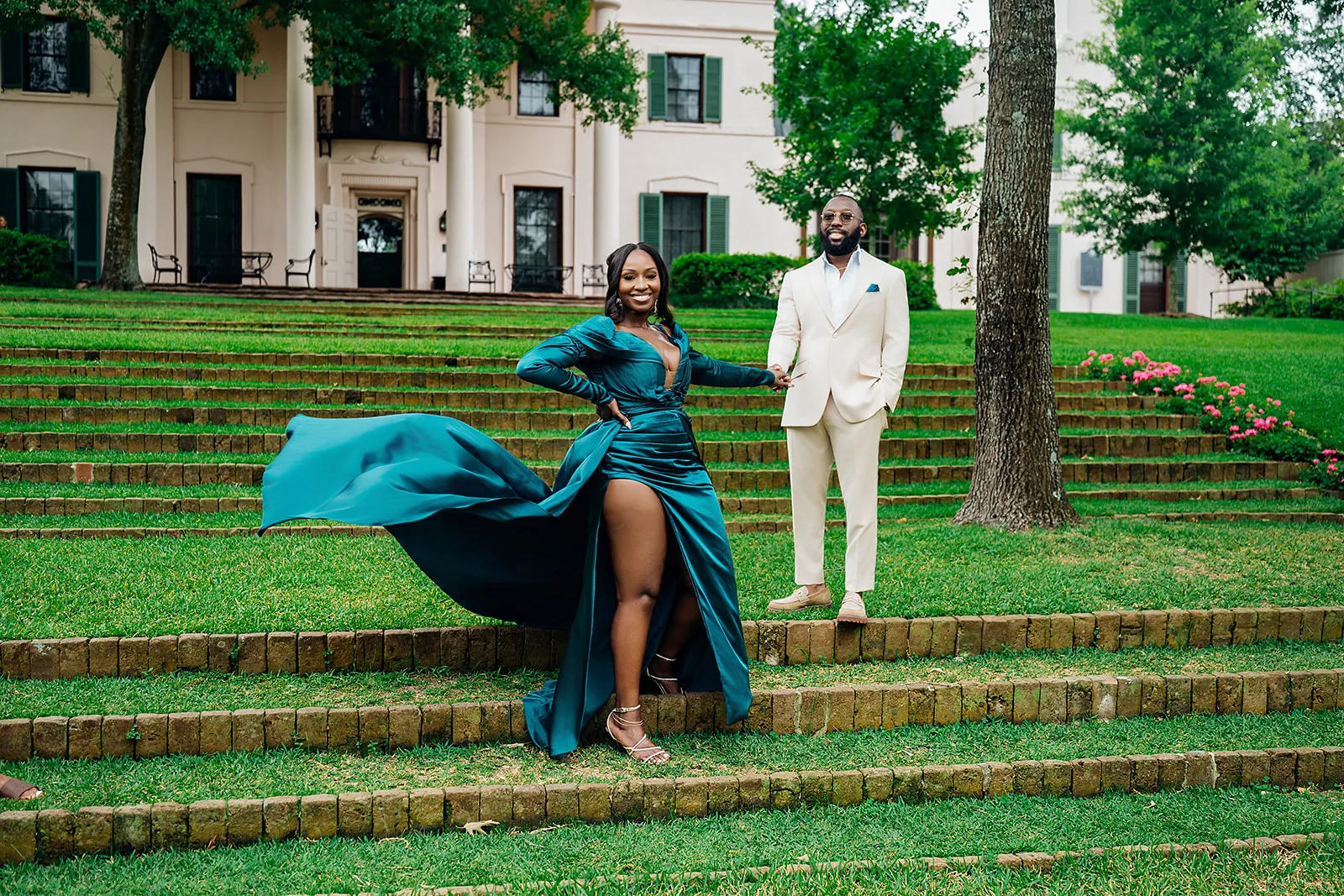 Couple in emerald gown and cream suit on brick steps of a mansion