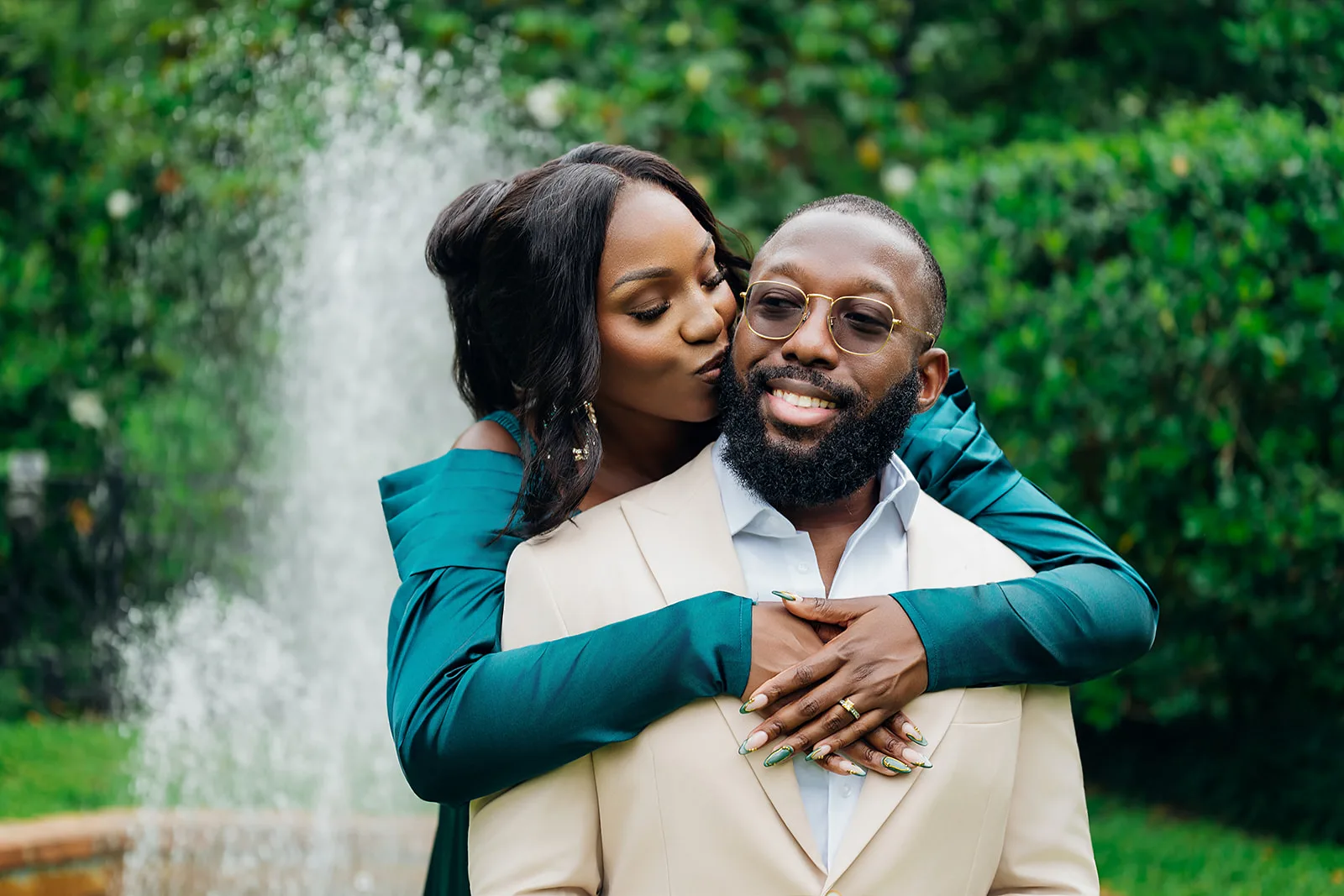 Fiancée kissing partner in front of garden fountain