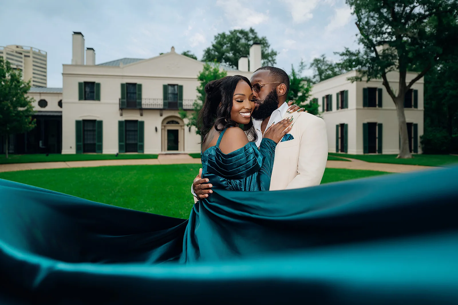 Couple embracing outside mansion with flowing emerald gown