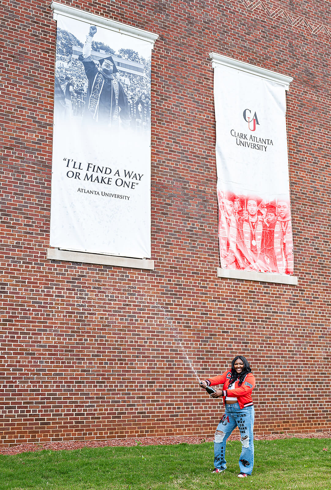 Clark Atlanta University graduate spraying champagne under campus heritage banners