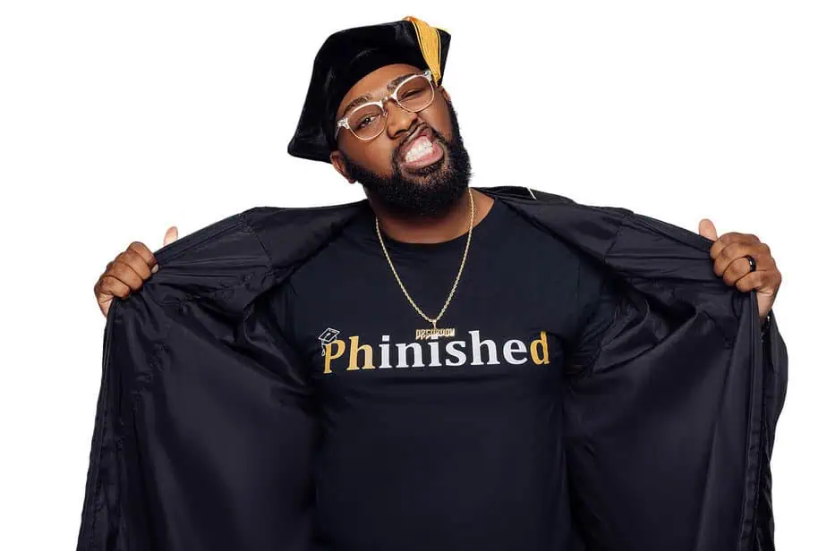 PhD graduate in tam and Phinished shirt opening doctoral gown in studio