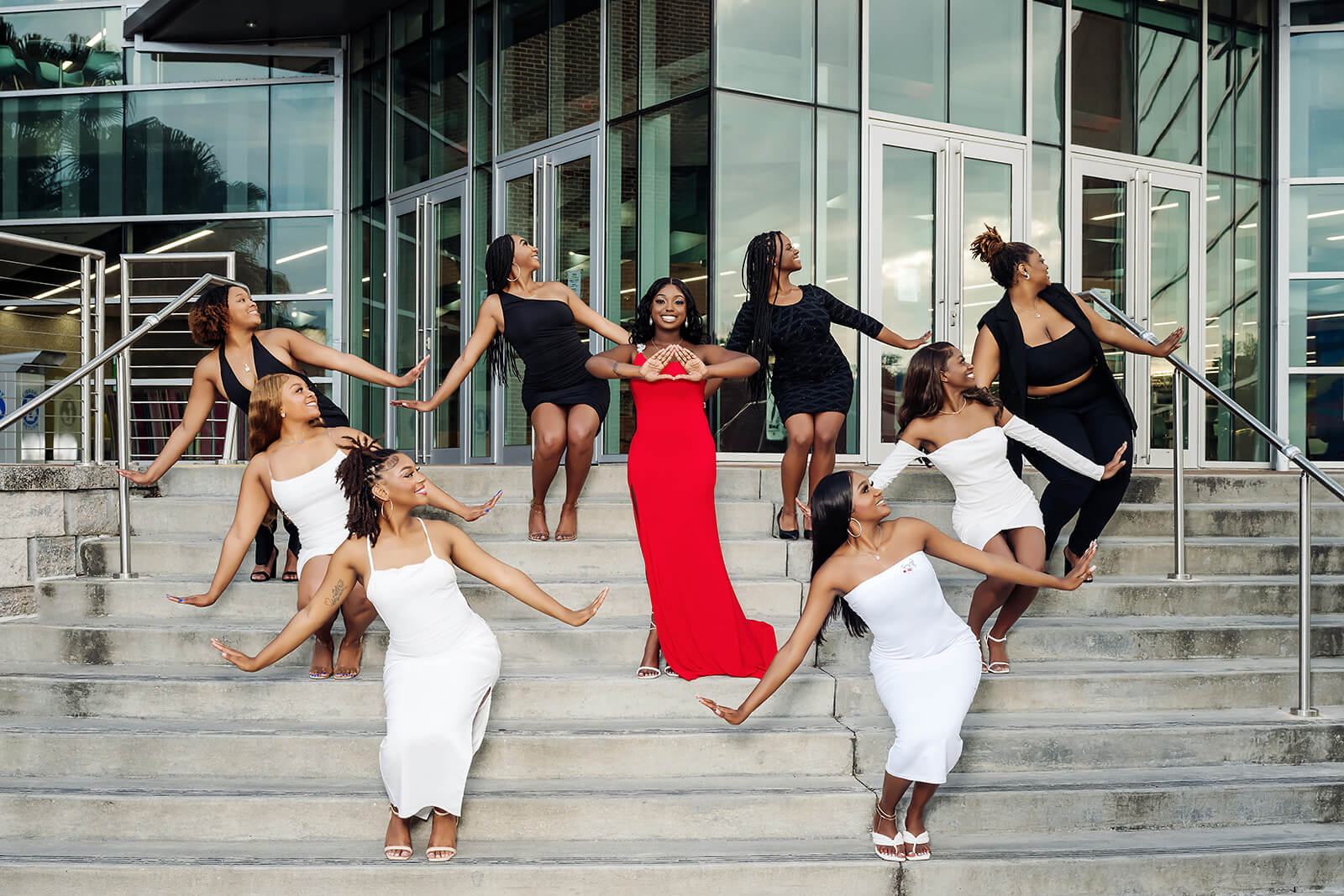 Sorority line graduation photoshoot on glass building steps with red and black dresses