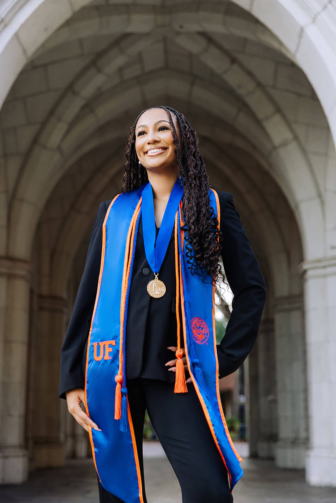University of Florida graduate with UF stoles and medallion under stone archway