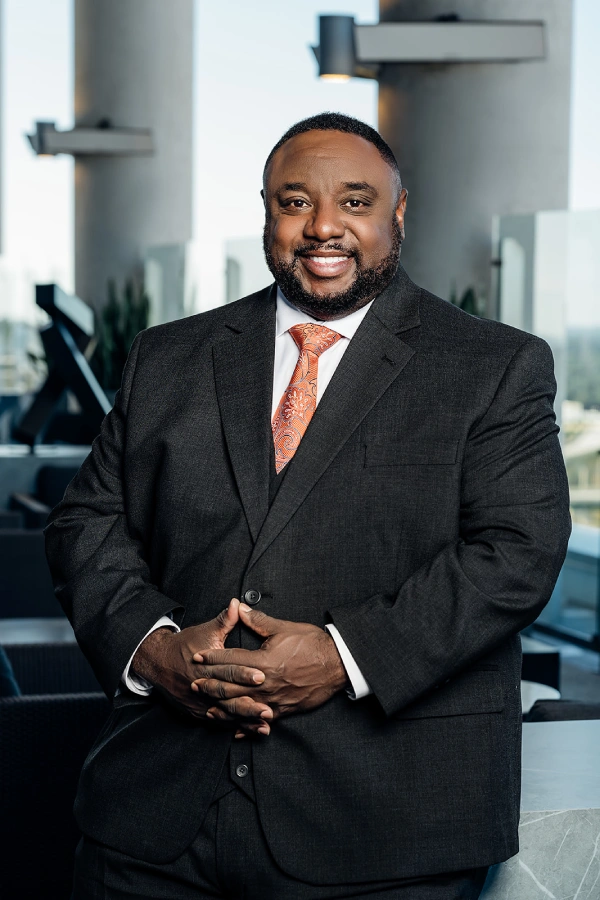 Executive headshot of a man in a charcoal suit and orange paisley tie