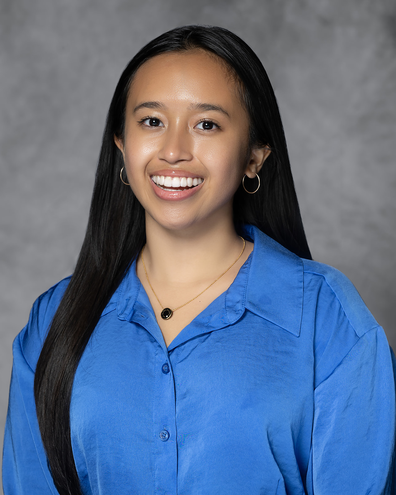 Studio headshot of a young professional woman in a blue blouse