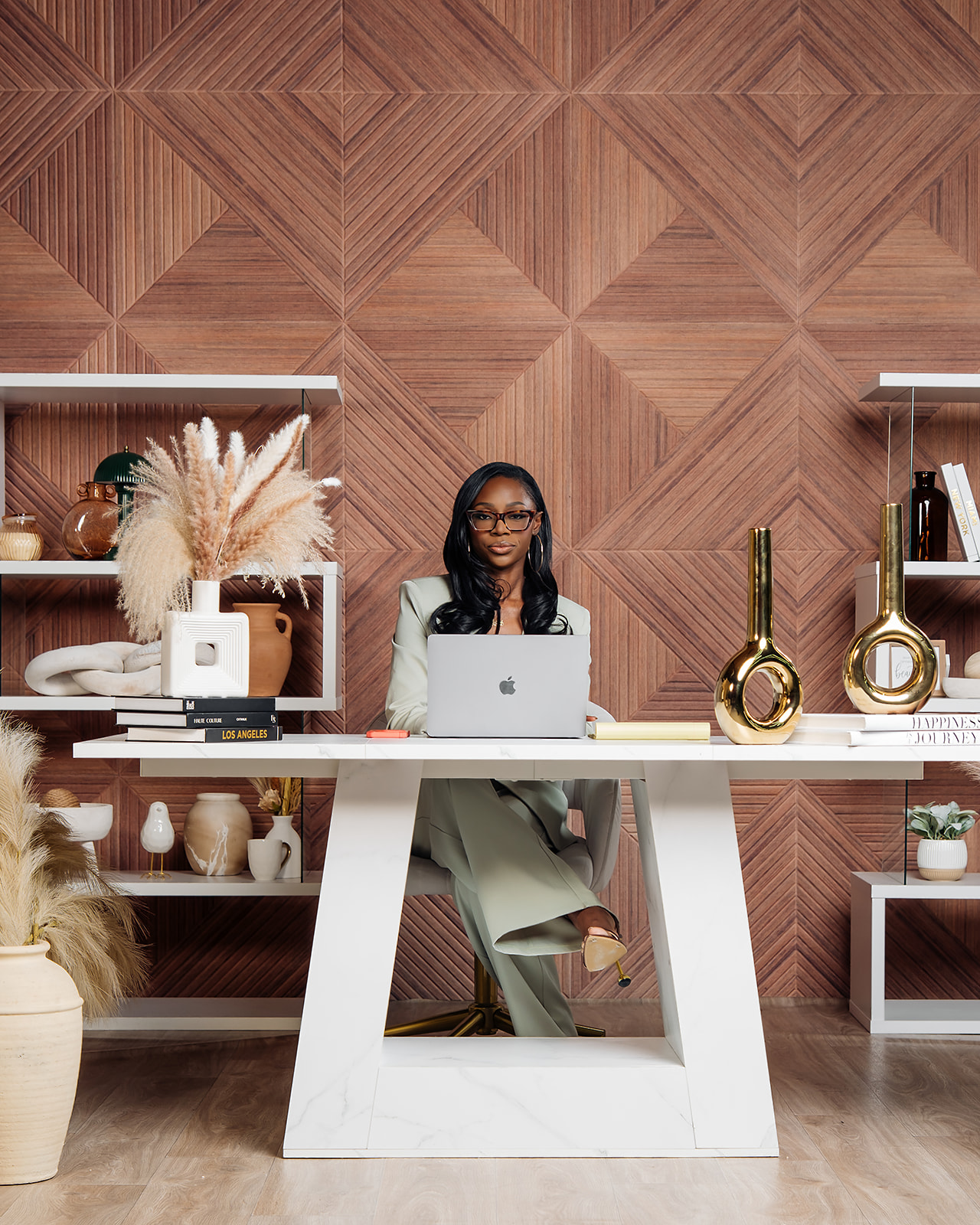 Wide shot of woman working at marble desk with pampas and gold decor