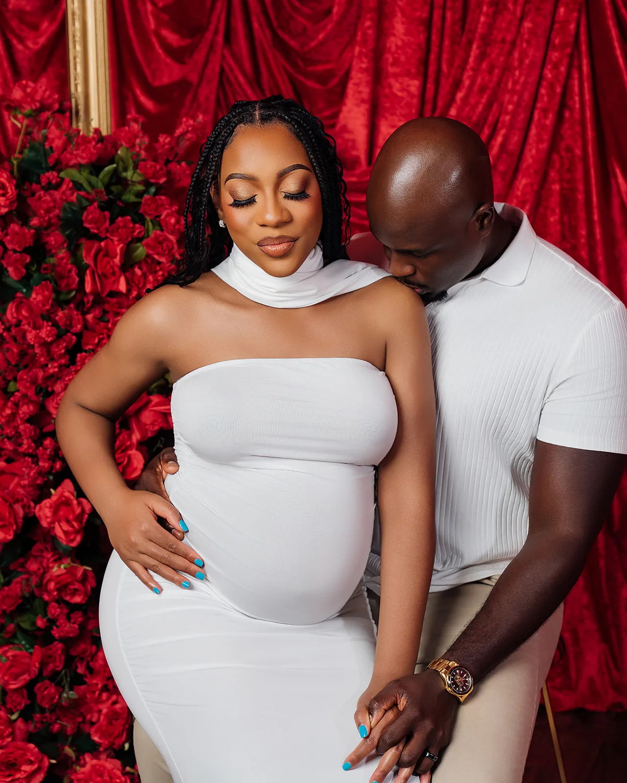 Maternity couple portrait — partners in white against red rose backdrop