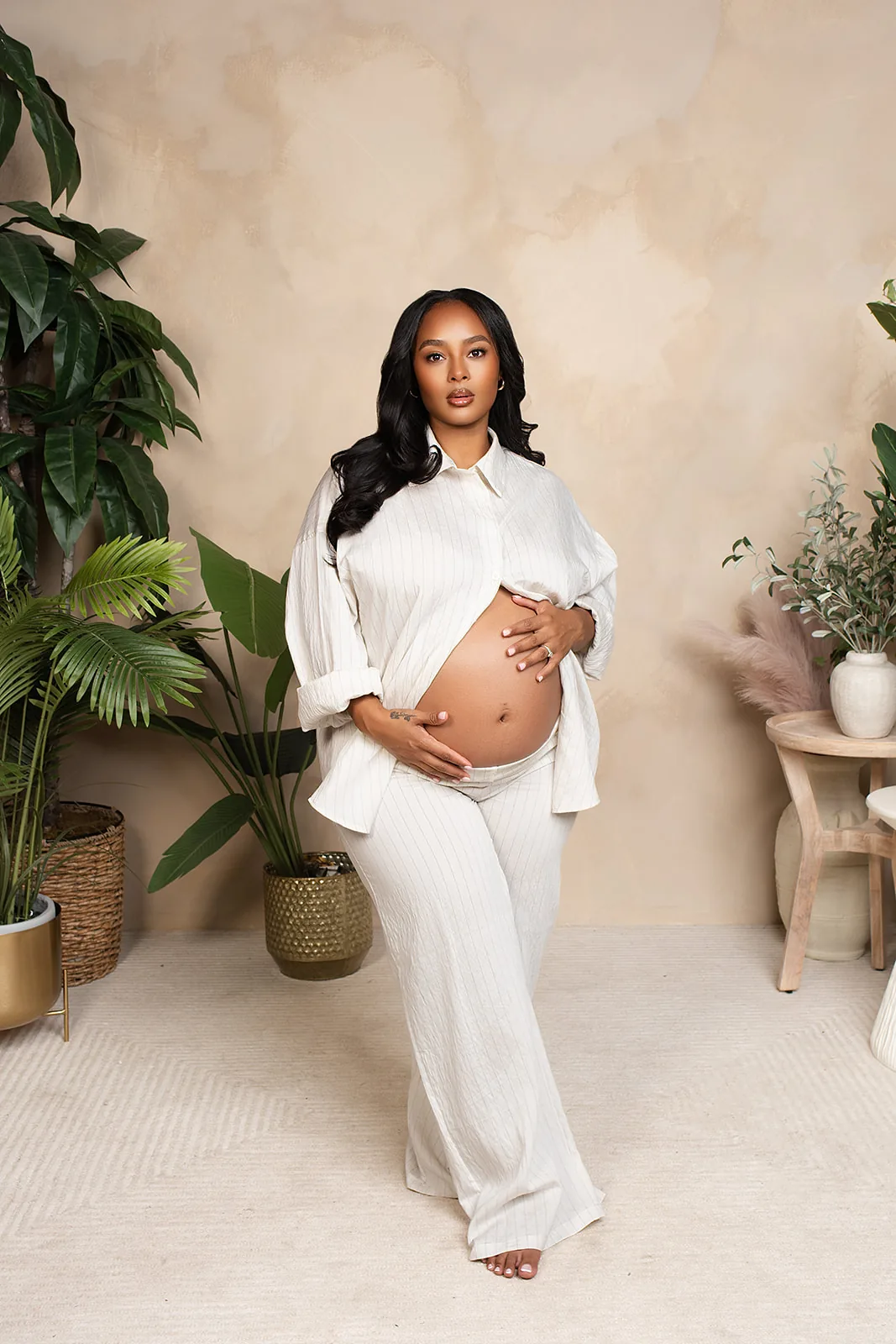 Maternity portrait — expecting mother in cream linen among plants