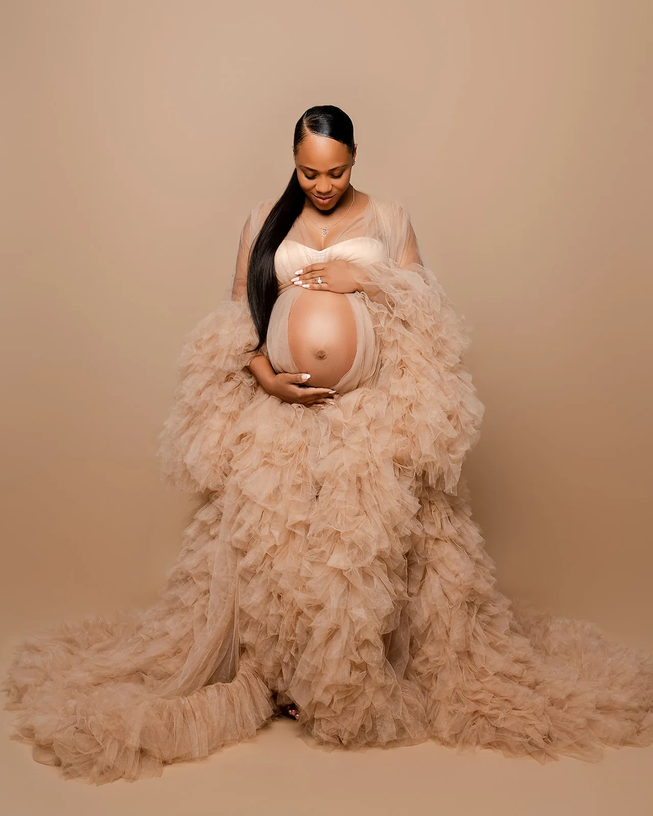 Maternity portrait — expecting mother in nude tulle ruffled gown