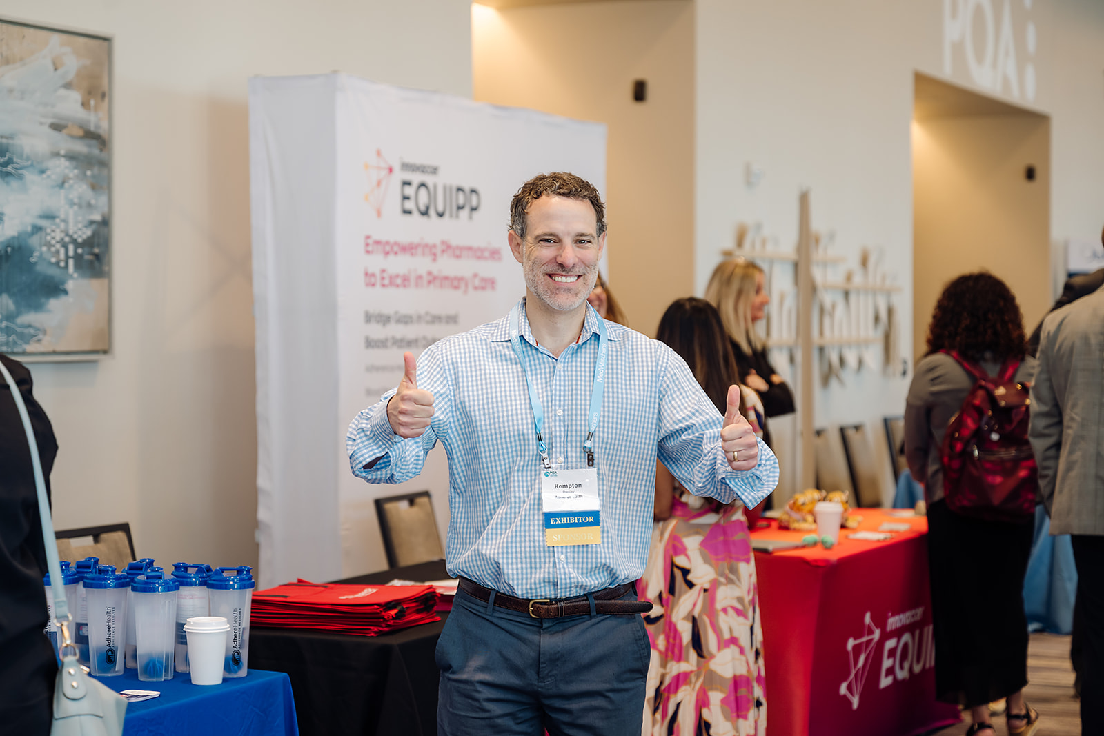 Smiling exhibitor giving thumbs up at PQA conference Innovaccer EQUIPP booth