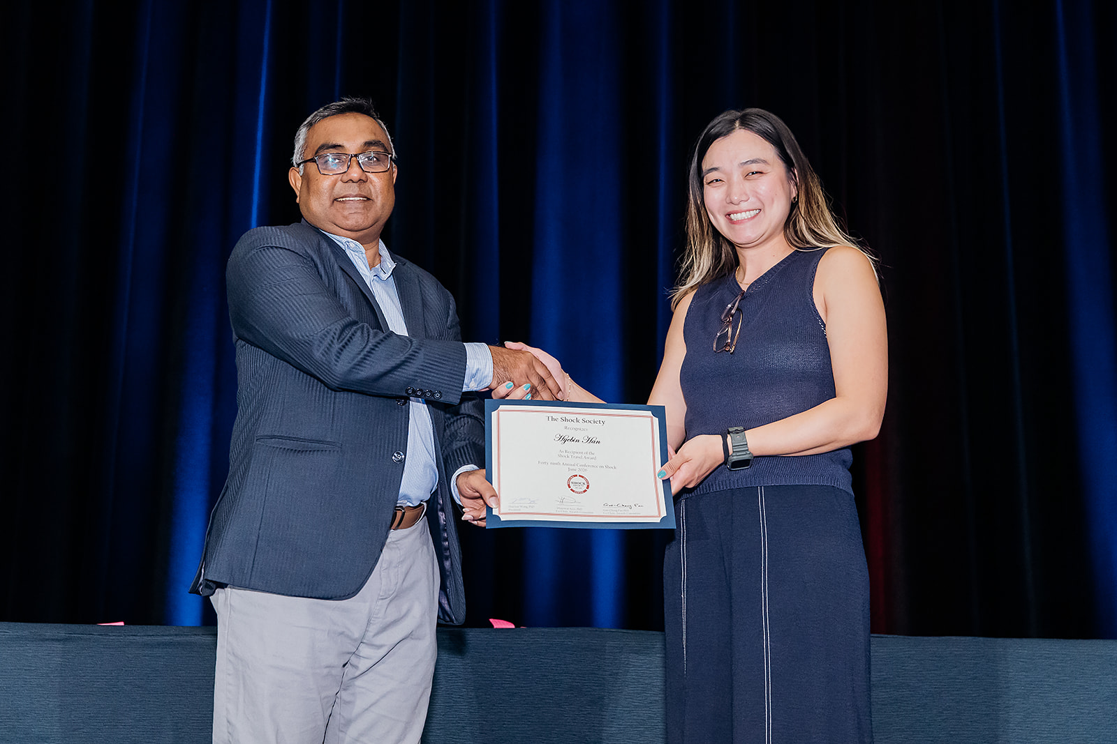 Shock Society Travel Award recipient handshake on stage in Las Vegas