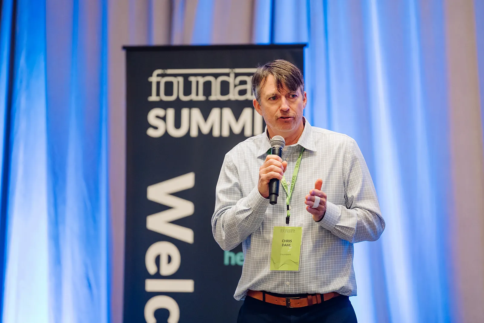 Foundant leadership keynote speaker Chris Dahl delivering remarks with a microphone at the Tampa Summit