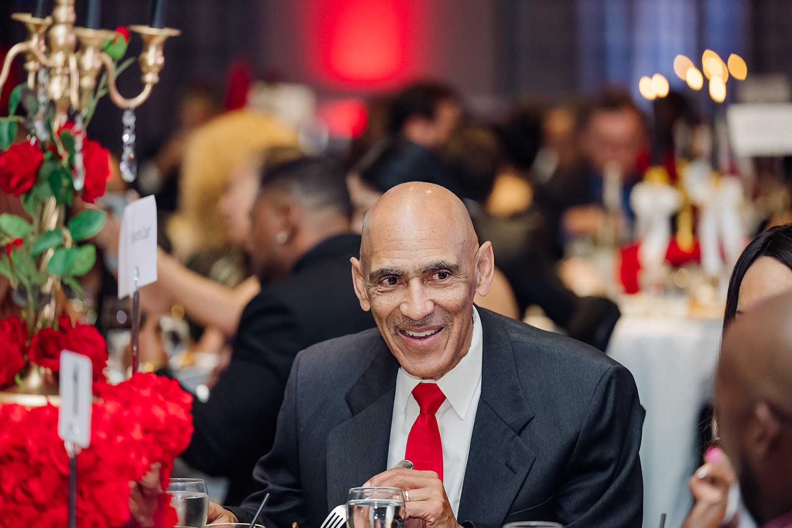 Tony Dungy smiling at a corporate gala dinner with red rose centerpieces