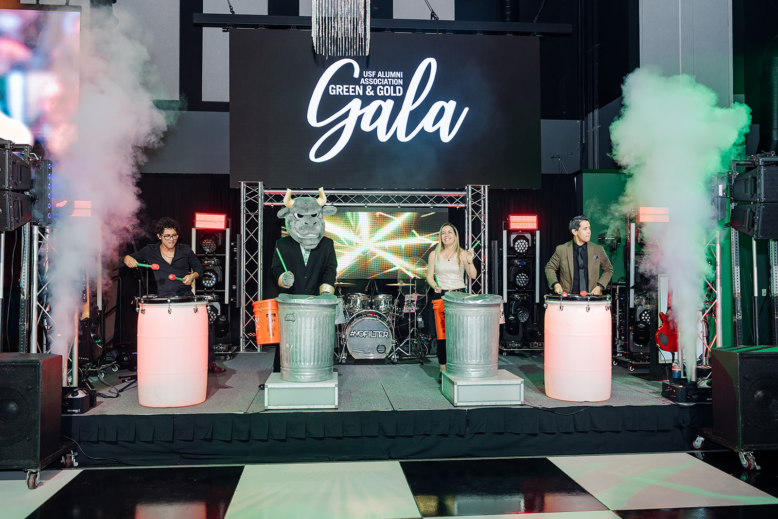 Rocky the Bull mascot performing a drum line on stage at the USF Green and Gold Gala