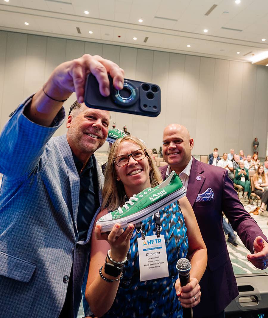 Keynote speaker taking a selfie with attendees in front of a full conference room