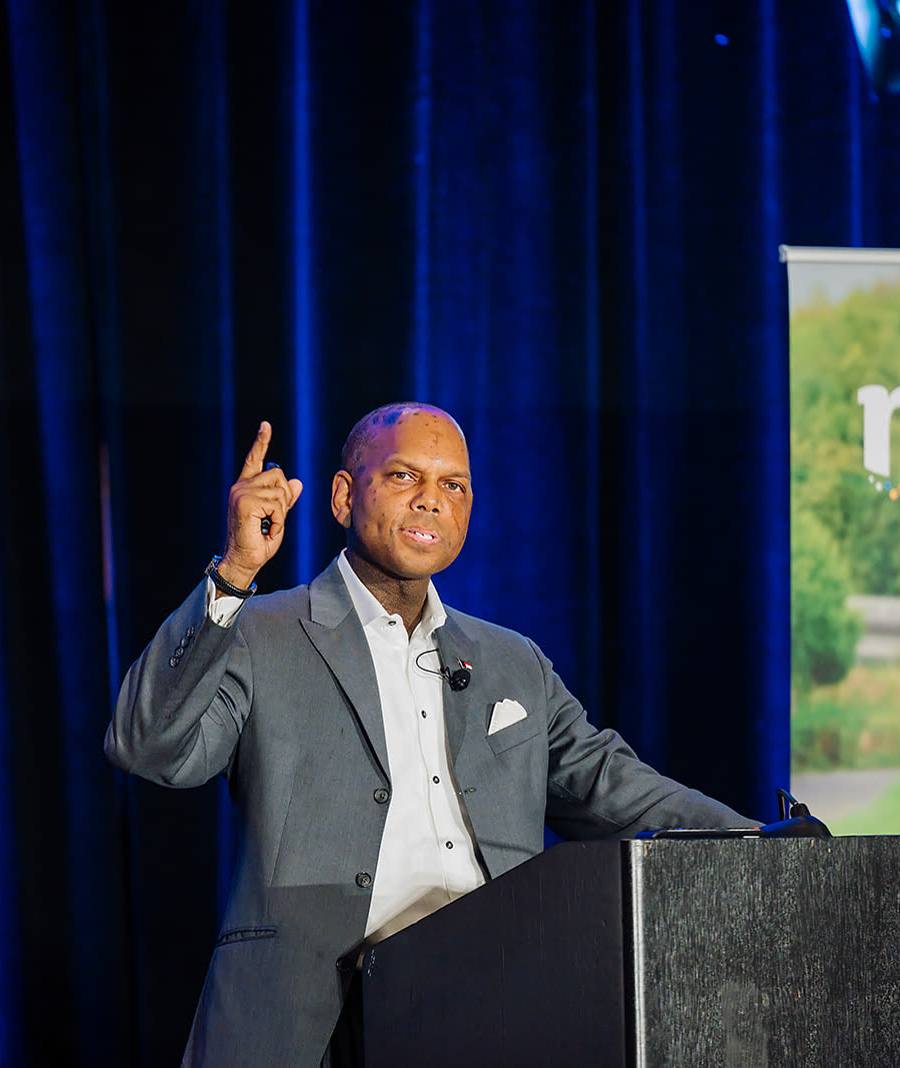Keynote speaker gesturing from the podium while making a point to the room