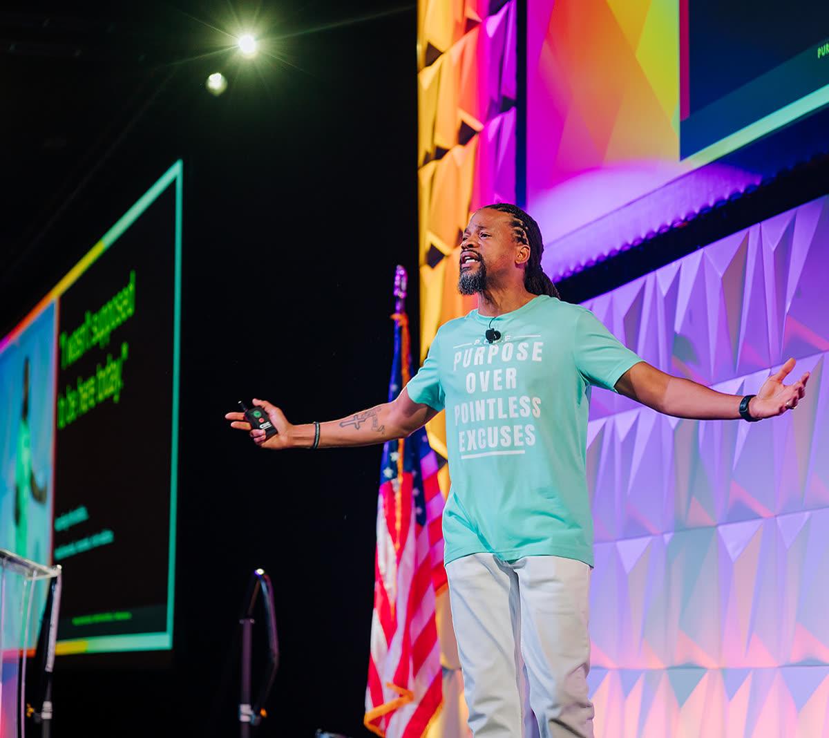 Keynote speaker with arms open addressing a full conference general session