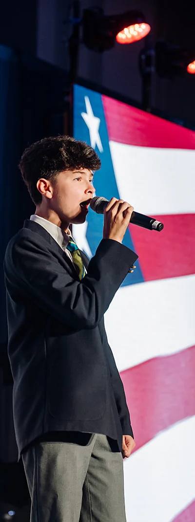 Young vocalist performing the national anthem on stage with American flag LED backdrop at USHCC National Conference in Atlanta