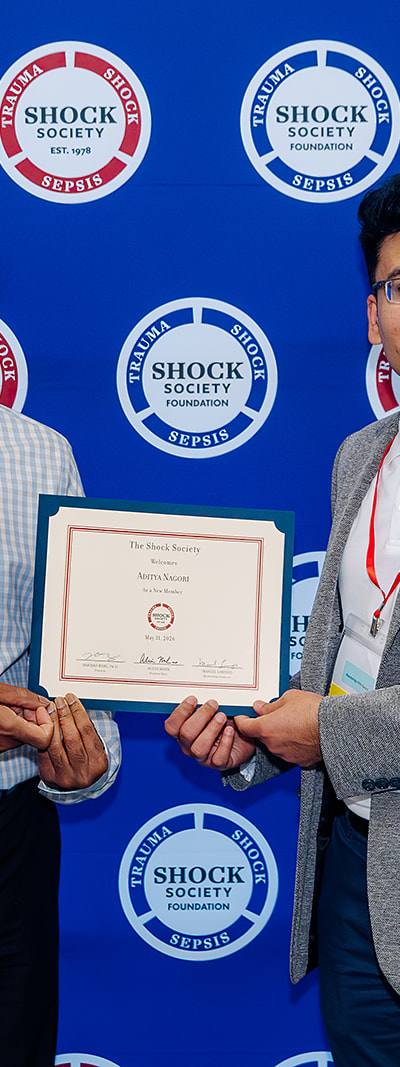 Shock Society new member recognition with certificate on step-and-repeat backdrop in Las Vegas