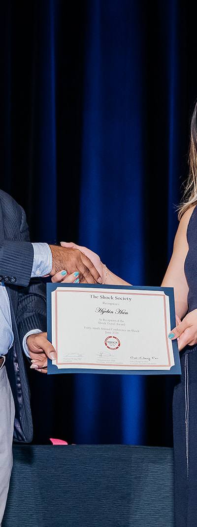 Shock Society Travel Award recipient handshake on stage in Las Vegas