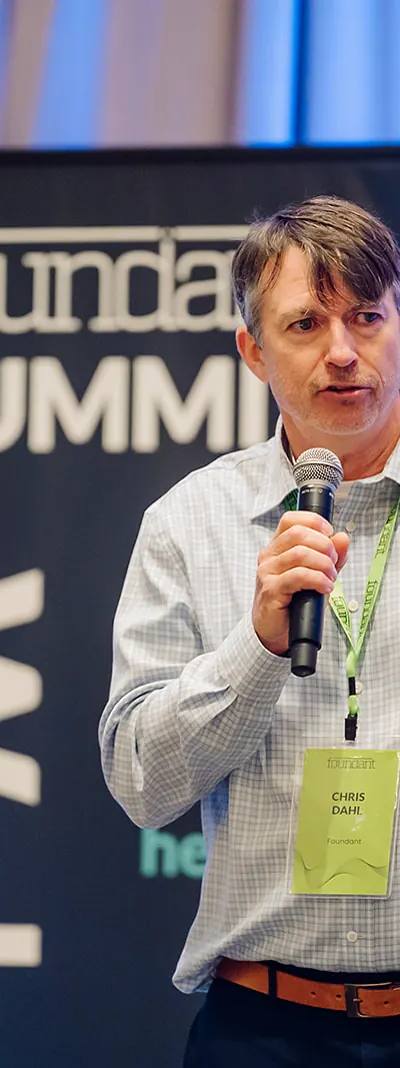 Foundant leadership keynote speaker Chris Dahl delivering remarks with a microphone at the Tampa Summit