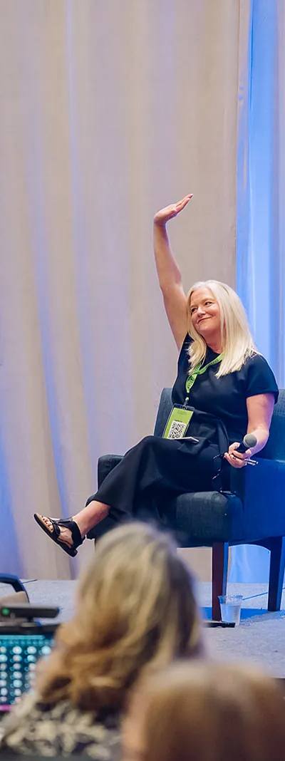 Three panelists on stage raising hands during a Foundant Summit panel discussion in Tampa