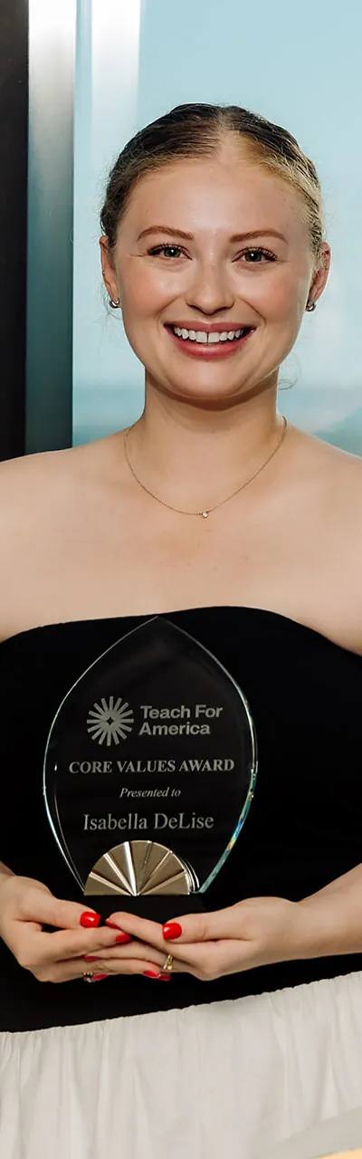 Teach For America Core Values Award recipient holding her award with the downtown Tampa skyline behind her