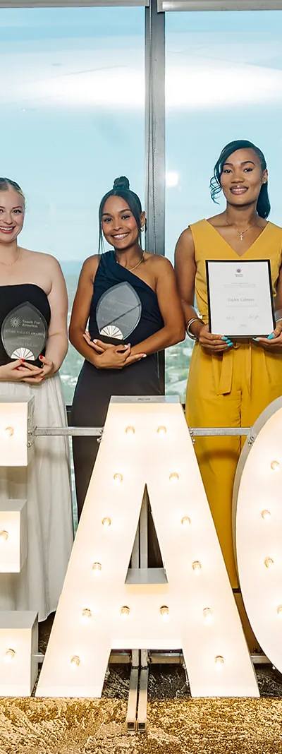 Teach For America Core Values Award recipients posed behind illuminated TEACH marquee letters with the Tampa skyline in the background