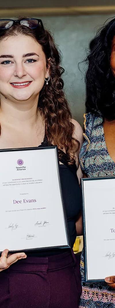 Two Teach For America 2024 corps members smiling with framed recognition certificates at the Tampa ceremony